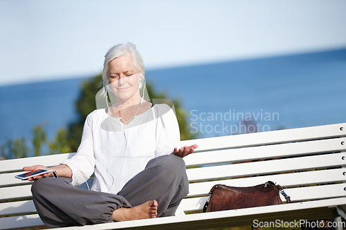 Image of Relaxing with some tranquil music. Shot of a mature woman listening to music while doing a relaxation exercise outdoors.