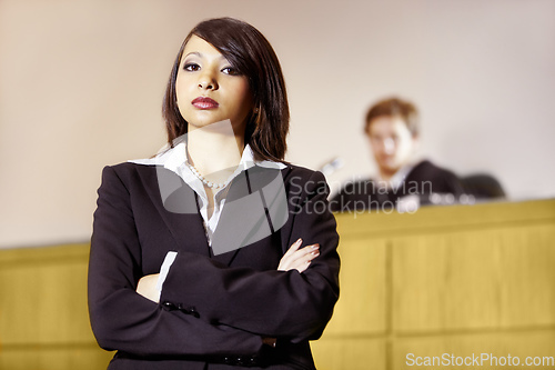 Image of Well-qualified to win in court. Stern young advocate standing in the courtroom with her arms folded.