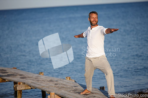 Image of Warrior by the sea. Shot of a handsome mature man doing yoga beside the ocean.