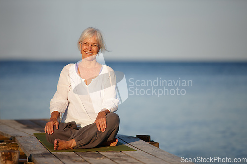 Image of The best yoga spot. Portrait of an attractive mature woman doing yoga on a pier out on the ocean.