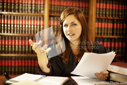 Image of Setting a legal precedence. Attractive young judge sitting at her desk discussing the law.