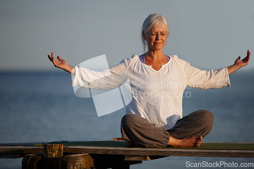 Image of Become calm like the ocean. Full length shot of an attractive mature woman doing yoga on a pier out on the ocean.