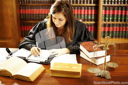 Image of Shes an expert in the legal world. Shot of a young legal professional sitting at her desk in a study.