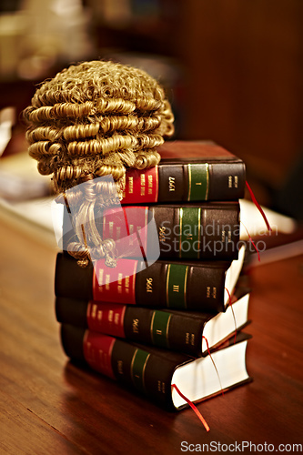 Image of Knowledge of the law is crucial for a fair trial. Shot of legal books and a wig on top of a table.