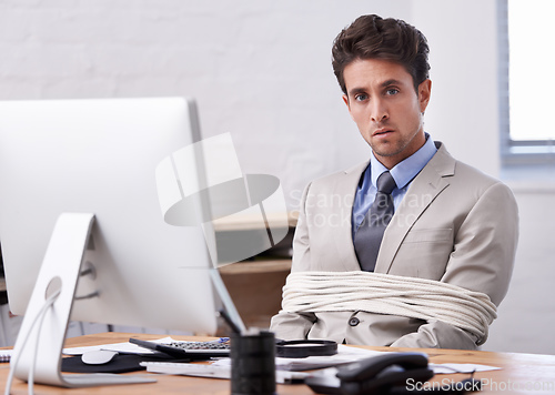 Image of Hes always stuck to his desk. A handsome young businessman tied up and sitting at his desk.