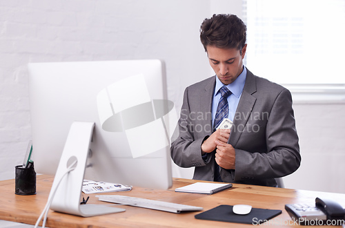 Image of Pocketing some cash. A young businessman putting cash in his pocket.