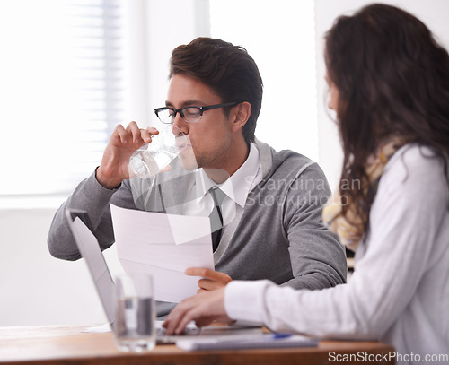 Image of This interview is giving me a dry mouth. A young man drinking water during an interview.