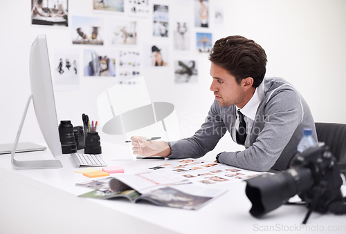 Image of Making his final selection. A photographer looking at his images in his office.