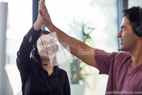 Image of Always proving a quality customer service experience. Shot of two call centre agents giving each other a high five at the office.