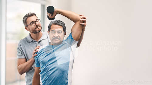 Image of Proper technique is the main focus. Shot of a senior man exercising with dumbbells during a rehabilitation session with his physiotherapist.