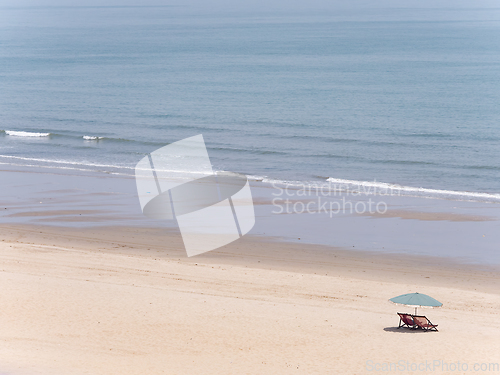 Image of Deck chairs and parasol on empty beach