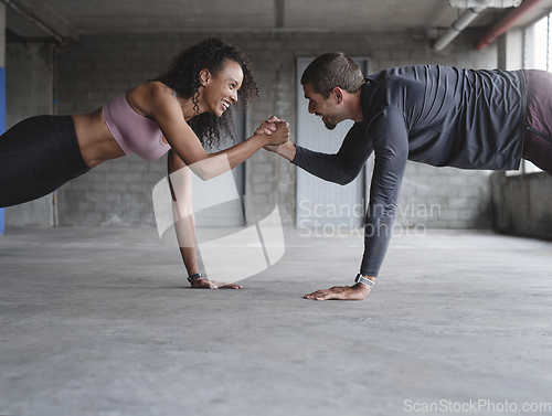 Image of We can withstand anything together. Shot of a sporty young couple holding hands while exercising together inside an underground parking lot.