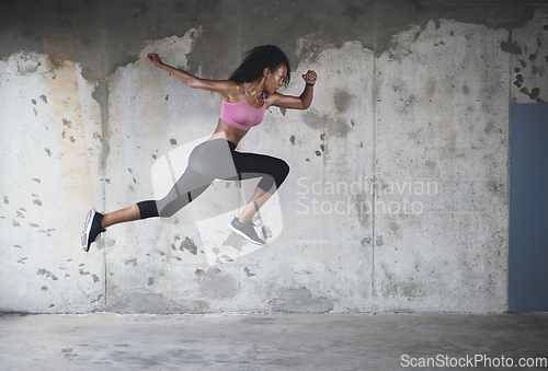 Image of Springing back into action. Full length shot of an athletic young sportswoman jumping in the air against a wall outdoors.