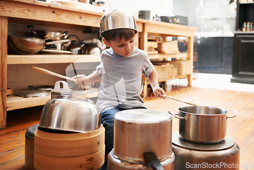 Image of Rock star in the making. A young boy playing drums on pots and pans.