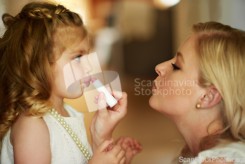 Image of Dressing up her little princess. Cropped shot of a mother applying lipstick to her little daughter at home.