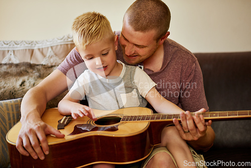 Image of Time for another guitar lesson with Dad. Cropped shot of a father and his little son playing the guitar together at home.
