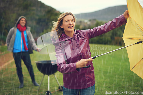 Image of We wont let a little bad weather stop our barbeque. Shot of a couple trying to barbecue in the rain.