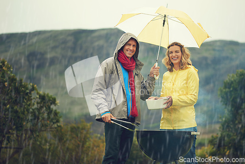 Image of Come rain or shine. Shot of a couple happily barbecuing in the rain.