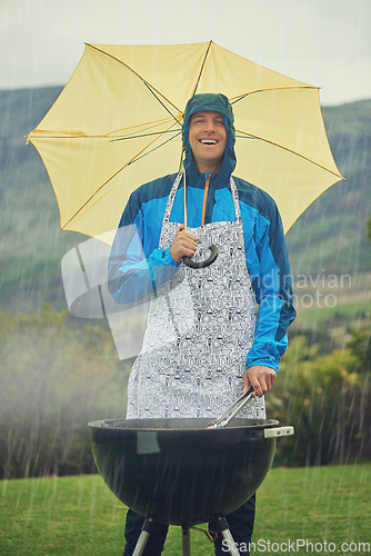 Image of Its like liquid sunshine. Shot of a man happily barbecuing in the rain.