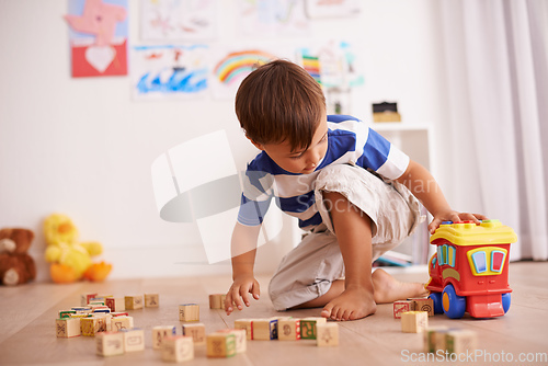 Image of Playing and learning. Shot of a little boy playing with his building blocks and toy truck in his room.