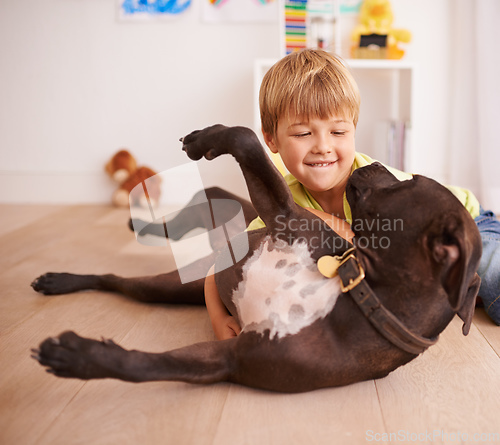 Image of Every little boy should have his own dog. A little boy playing with his dog in his room.