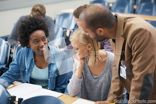 Image of A lecturer is always on hand if you have questions. A young man speaking to two girls sitting in a lecture room.