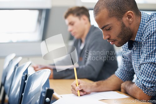 Image of It all comes down to the test.... Two male students writing exam in a lecture hall.