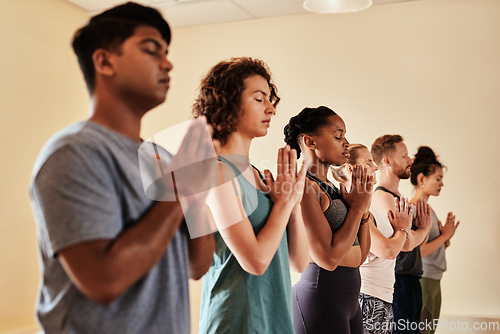 Image of Yoga is a work of heart. Shot of a group of young men and women meditating in a yoga class.