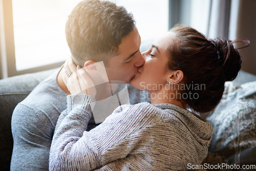 Image of Passionate kisses on the couch. Shot of an affectionate young couple kissing on the sofa at home.