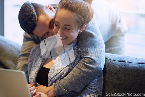 Image of Showering her with affection. Shot of an affectionate young couple surfing the net while relaxing on the sofa at home.