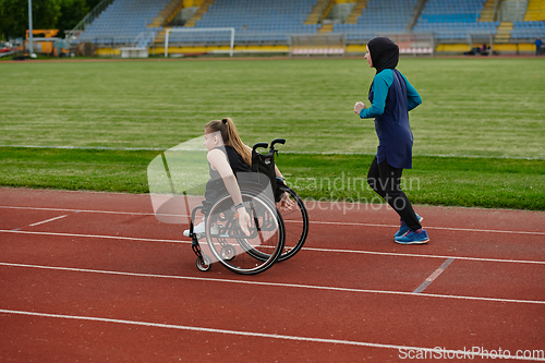 Image of A Muslim woman in a burqa running together with a woman in a wheelchair on the marathon course, preparing for future competitions.