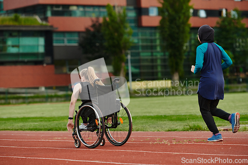 Image of A Muslim woman in a burqa running together with a woman in a wheelchair on the marathon course, preparing for future competitions.