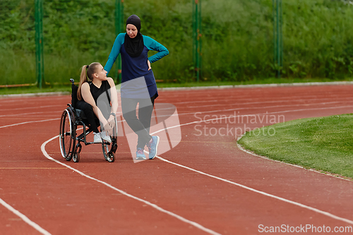 Image of A Muslim woman wearing a burqa resting with a woman with disability after a hard training session on the marathon course