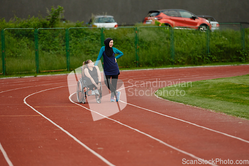 Image of A Muslim woman wearing a burqa resting with a woman with disability after a hard training session on the marathon course