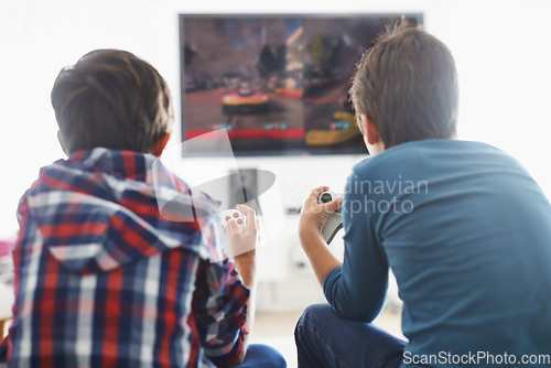 Image of Game Time. Rearview shot of two boys playing a video game in the living room.