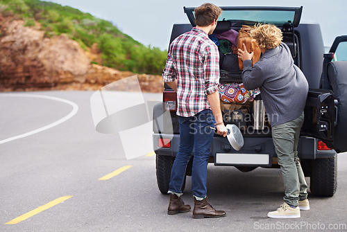 Image of We need a bigger truck. Shot of a two people stopped at the side of the road and repacking their truck.