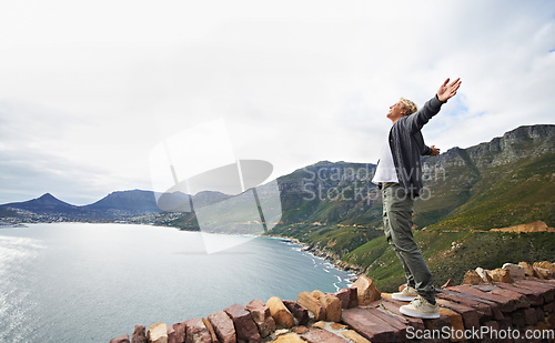 Image of Embracing the magnificence of nature. Shot of a young man standing on a wall looking at the natural scenery.