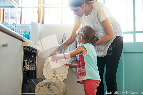 Image of One plate at a time. Shot of a mother and daughter busy at a dishwashing machine.