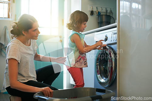 Image of She knows which buttons to press. Shot of a mother and daughter using a washing machine.