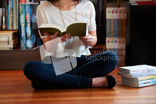 Image of Reading a few passages.... A cropped shot of a young woman sitting on the floor of a bookshop and reading.