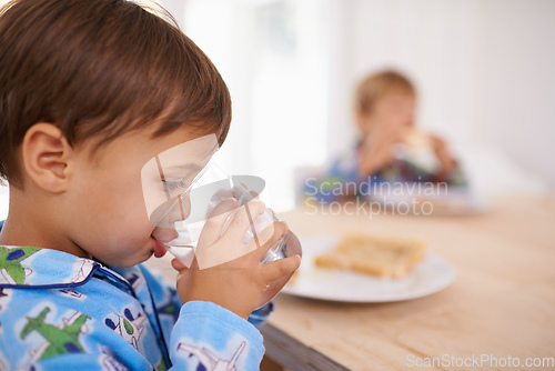 Image of Washing it down. A cute little boy having a drink of water with breakfast.