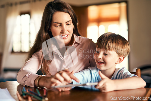 Image of Playing an active role in the learning process. Shot of a little boy using a digital tablet while doing homework with help from his mother.