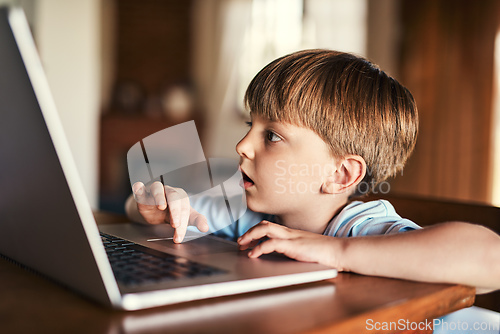 Image of Immersed in media. Shot of an adorable little boy using a laptop at home.