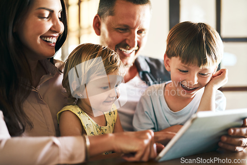 Image of Adding screen time to family time. Shot of a young family of four using a digital tablet together at home.