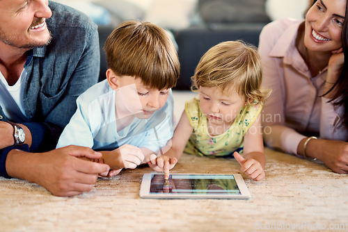 Image of The learning never ends with technology. Shot of a young family of four using a digital tablet together at home.