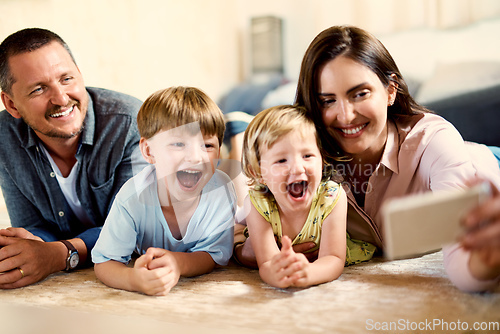 Image of Dont need to ask kids twice to take a selfie. Shot of a happy young family taking selfies together at home.