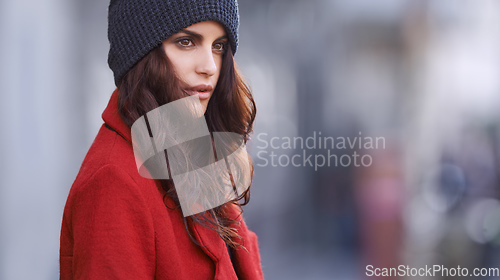 Image of When in doubt wear red. Shot of a beautiful young woman in winter clothing standing in an urban setting.