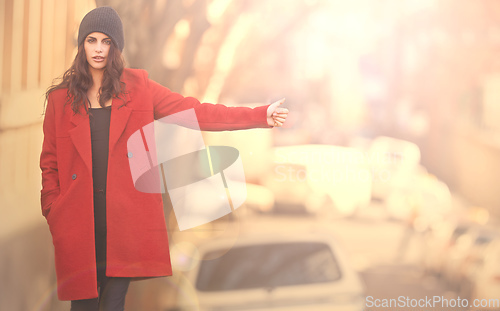 Image of Stay well travelled in winter. Portrait of a gorgeous young woman in a red winter coat hailing a cab in the city.