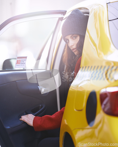 Image of On the move in the city. Portrait of a fashionable young woman getting into a cab in the city.