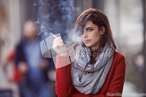 Image of Ill bring the smoke, you bring the fire. Portrait of a beautiful and fashionable young woman smoking a cigarette in an urban setting.